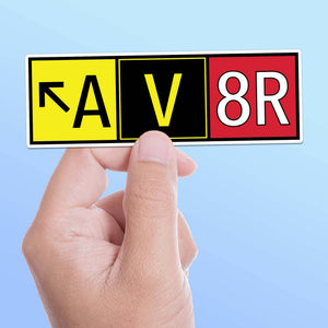 A sticker with 'AV8R' and runway directional signs in red, yellow, and black colors.