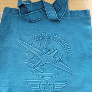 Yanks Air Museum and logo medium-sized tote bag with embossed airplane design, primarily in blue or green denim , with carrying straps.