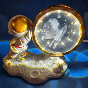 A LED night light featuring a 3D design of an astronaut with a crystal ball, displaying a cosmic scene.