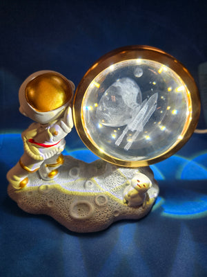 A LED night light featuring a 3D design of an astronaut with a crystal ball, displaying a cosmic scene.