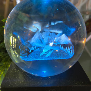 A blue crystal ball night light displaying a Northern Lights pattern with a float plane in the background.