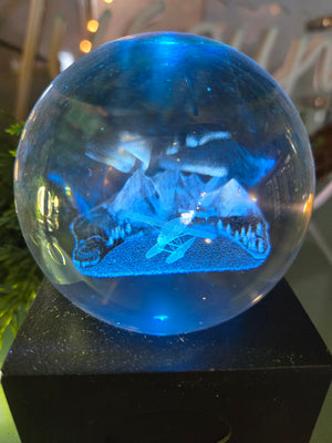 A blue crystal ball night light displaying a Northern Lights pattern with a float plane in the background.