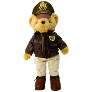 A plush toy bear wearing a military bomber jacket and hat, standing upright.