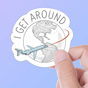 A round white sticker with a sketched world map and an airplane, and the text 'I GET AROUND' on it.