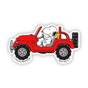 Sticker of Snoopy driving a red jeep with Woodstock on the hood, featuring 'Peanuts Worldwide' 