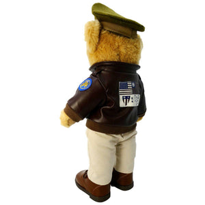 A plush toy bear wearing a military bomber jacket and hat, standing upright.