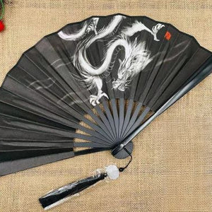Black folding fan with white dragon design on a textured surface