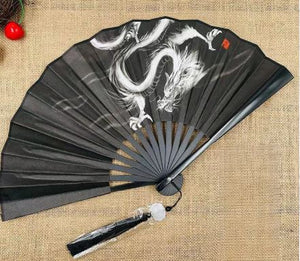 Black folding fan with white dragon design on a textured surface