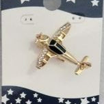 Gold airplane-shaped pin on a blue card with white stars