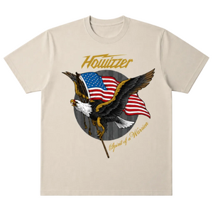 A beige crewneck t-shirt featuring a graphic of a bald eagle holding an American flag, with the text 'Howitzer' and 'Spirit of Warrior' printed in gold.