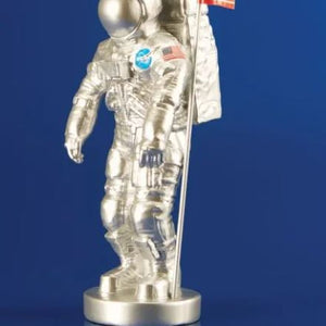 Clear astronaut figurine with NASA logo and American flag on a blue background