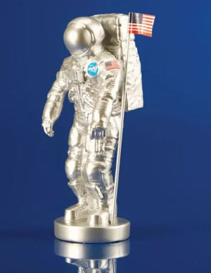 Clear astronaut figurine with NASA logo and American flag on a blue background