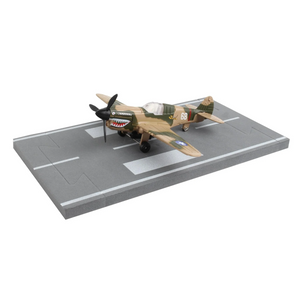 A scale model of a World War II P-51 Mustang fighter plane with a camouflage desert green and tan paint scheme, displayed on a gray miniature runway base against a white background.