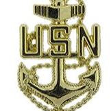 A gold-colored pin with the letters 'USN' and an anchor symbol, representing a US Navy Chief Petty Officer.