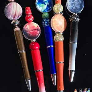 Decorative pens with unique bead designs on a black background