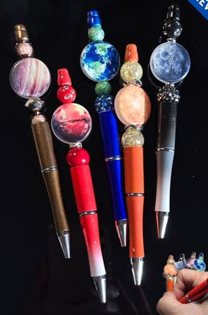 Decorative pens with unique bead designs on a black background