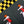 Close-up of a dark gray knit fabric with a black and yellow checkered section, pixel-art figures in red, white, and orange, and a diagonal split line running through the frame.