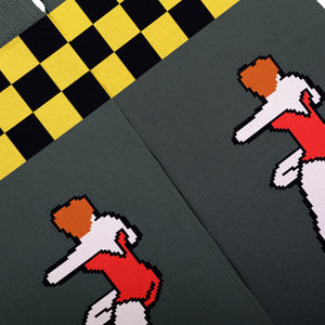 Close-up of a dark gray knit fabric with a black and yellow checkered section, pixel-art figures in red, white, and orange, and a diagonal split line running through the frame.