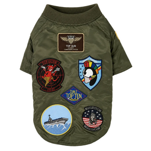 An olive green short-sleeve dog jacket decorated with multiple colorful military-style embroidered patches, shown on a plain white background.