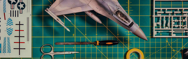Model airplane kit on a green cutting mat with tools