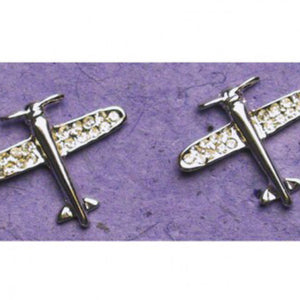 A pair of silver or gold fixed wing airplane earrings with crystals on a purple background