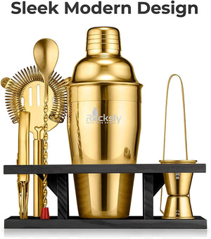 A set of gold-colored cocktail shakers and tools including a shaker bottle, a strainer, a jigger, and a spoon, displayed on a black stand with 'SLEAKY MODERN DESIGN' text overlay.