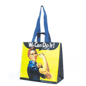 A large tote bag featuring a printed image of Rosie the Riveter with the text 'We Can Do It' on a yellow background, with blue straps.