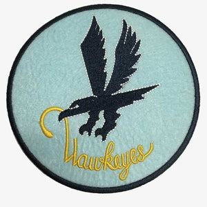 A round patch with a blue background featuring a black silhouette of a diving hawk with a yellow beak, and the word 'HAWKEYES' written below the hawk.