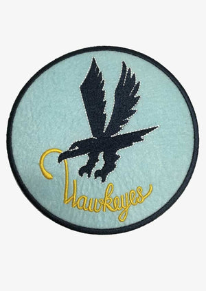A round patch with a blue background featuring a black silhouette of a diving hawk with a yellow beak, and the word 'HAWKEYES' written below the hawk.