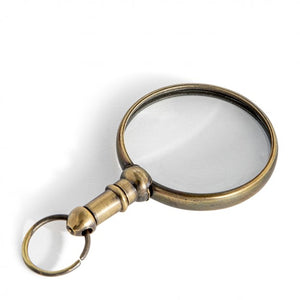 A small brass magnifying glass with a bronze finish, featuring a circular body and a handle for holding.