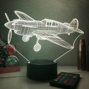 A 3D optical illusion lamp featuring a silhouette of a P-40 Warhawk aircraft with color-changing LED lights, placed on a black base.
