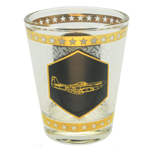 A shot glass with gold foil accents and an etched image of a P-51 Mustang airplane on a black background.