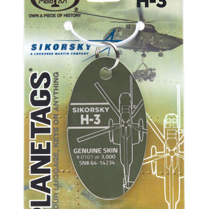 A Sikorsky H-3 Yanks Plane Tag made from retired aircraft fuselage, with a green background featuring an illustration of the helicopter and its details. The tag has a metal ring for attachment and is labeled with 'SIKORSKY' and 'H-3' designations.