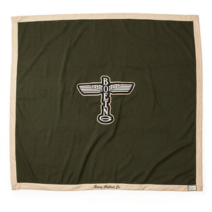 A khaki-colored blanket with tan trim and the Boeing logo on the front, displaying the text 'BOEING AIRPLANE CO.'