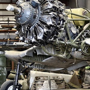  Donate to the restoration F4U Corsair aircraft on display, with visible signs of wear and restoration needed.